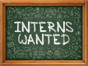 A chalkboard that has "Interns Wanted" writen on it.