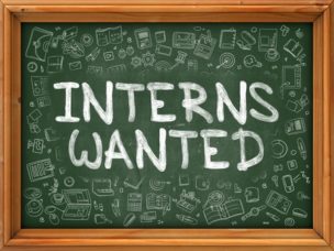 A chalkboard that has "Interns Wanted" writen on it.