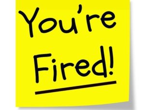 A yellow sticky memo pad note with black writing that says "you're fired!"