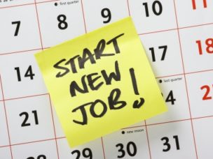 Hand written reminder in caps to "start new job" on a yellow sticky note stuck to a calendar background.