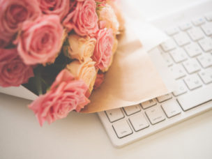 Closeup of a bouquet of pink and beige roses on white computer keyboard.