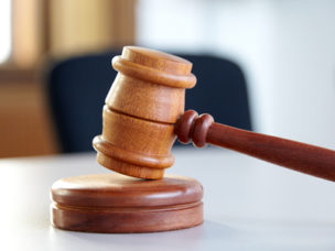 Closeup of a wooden gavel on a surface.