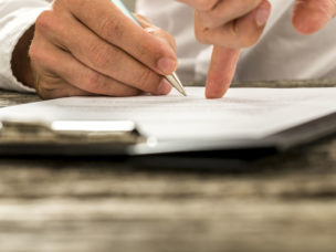 Closeup of male hand pointing where to sign a contract.