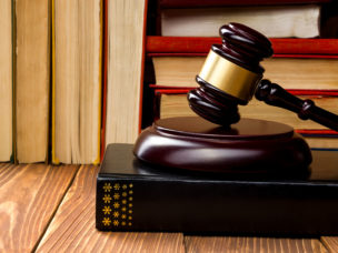 Wooden gavel at rest with law books in the background.