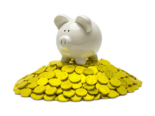 A white glass piggy bank on top of golden coins.
