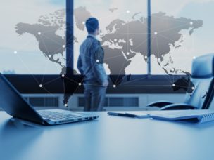 Businessman looking out office windows at continental map