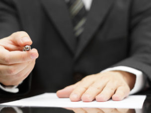 Man offering pen to sign document