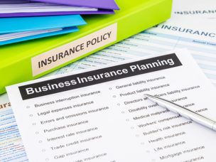 insurance binders next to a worksheet on Business Insurance Planning