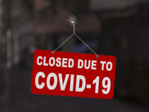 red sign on a shop window reading "closed due to COVID-19"
