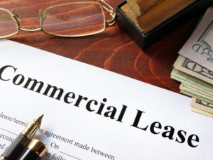 commercial lease paper on desk with pen, glasses, and cash