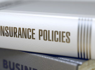Stack of books with a book titled "Insurance Policies." Book title on spine. Closeup view.