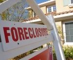 a white and red sign that has the word "foreclosure" and a yellow house in the background