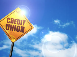 credit union labeled on a yellow traffic sign with bright blue sky and white clouds in the back