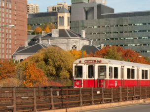 red line subway train of mbta with bulidings in the background