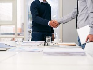 two men shaking hands in a business work space