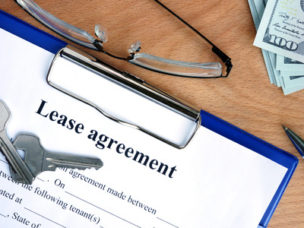 lease agreement document with money and keys on a wood background