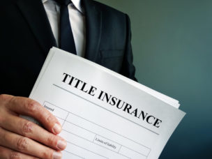 Man in a suit holding documents reading "Title Insurance"