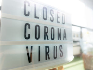 sign reading "Closed Coronavirus" on a storefront window