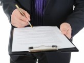 a man signing a paper on a clipboard