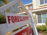 a white and red sign that has the word "foreclosure" and a yellow house in the background
