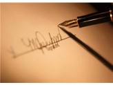 a signature on a paper and a tip of a pen in the corner