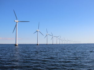 Perspective line of ocean wind mills with dark water and sky