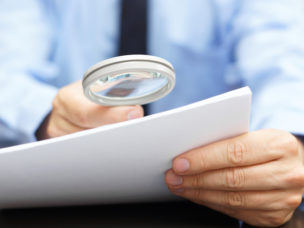 Businessman looking through a magnifying glass to contract