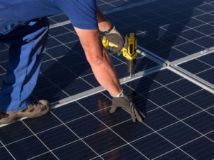 man installing roof-mounted solar array