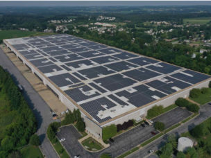 photo of large commercial building with rooftop solar array and trees surrounding
