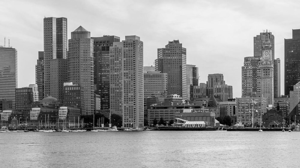 Black and white photo of downtown Boston with skyscrapers overlooking Boston Harbor