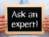 a man holding a small chalkboard that has " Ask an expert!" on it