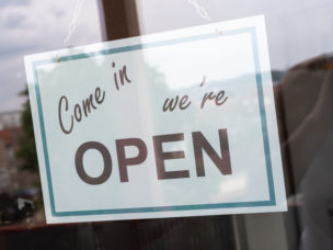 sign reading "Come in We're Open" hanging in a window